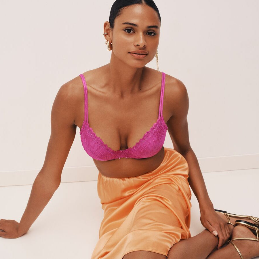 Woman wearing a pink bra and peach skirt on a white background