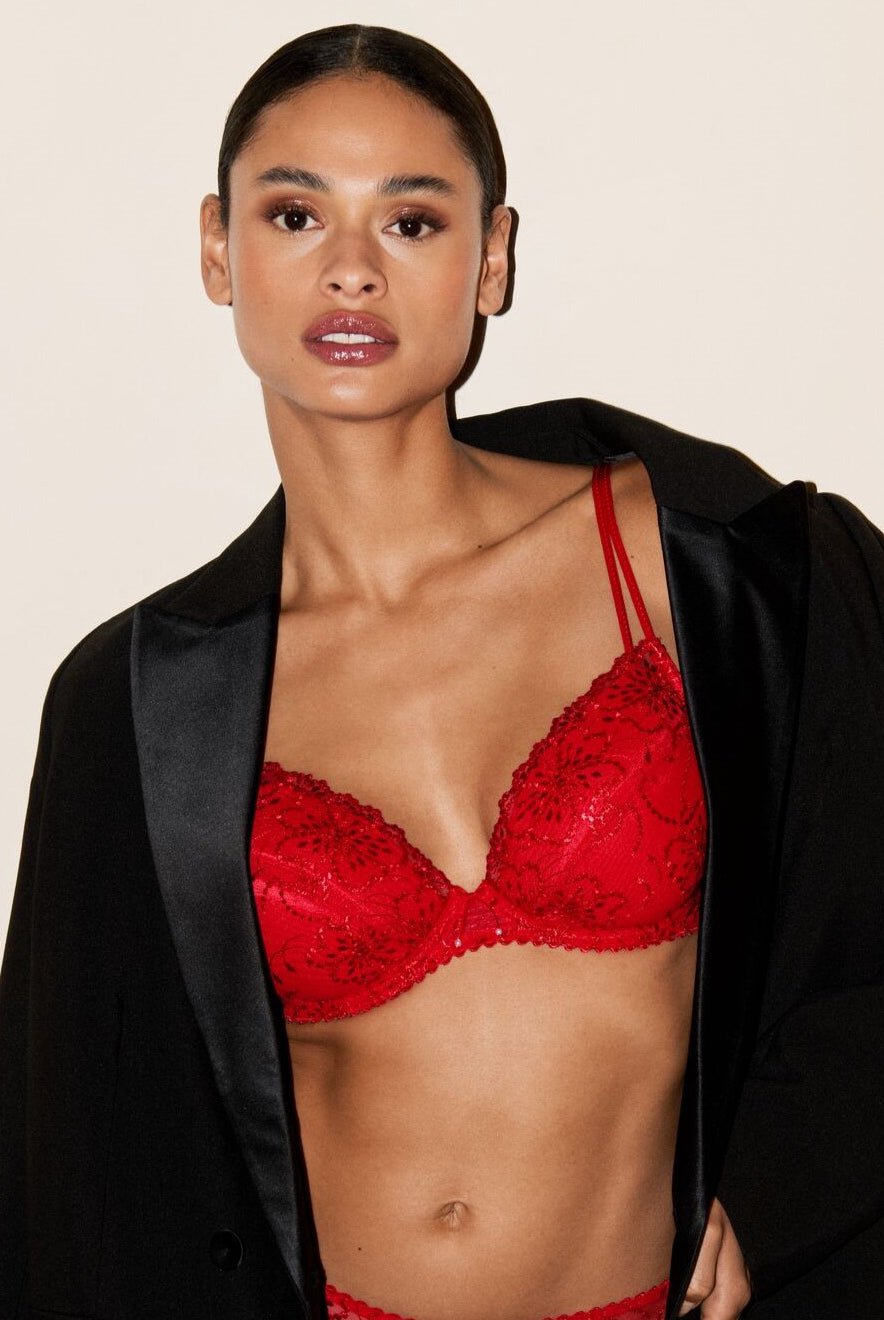 Woman wearing a red bra and black jacket on a beige background
