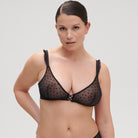 Black wire-free triangle bra made from seductive sheer tulle, flocked with velvet spots, and finished with ruffle trims.