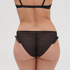 Black bikini brief made from sheer fabric with ruched back and polka dots.
