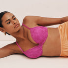 Woman wearing a pink lace bra and orange underwear on a white background