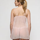 Woman wearing a sheer pink nightgown against a white background